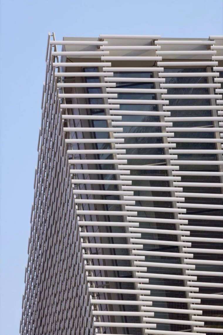 A detailed view of the terracotta baguettes, highlighting their design and how they cast beautiful patterns of light and shadow on the façade.